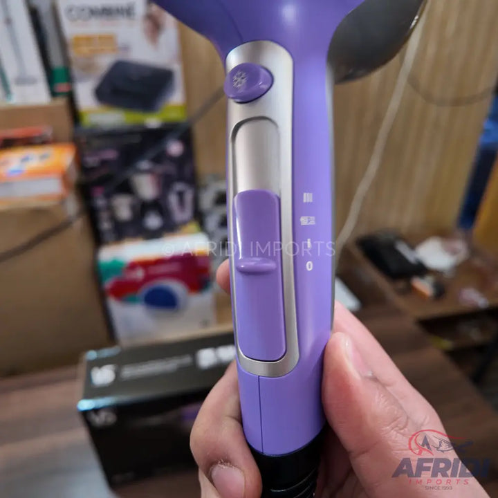Purple hair dryer with a silver control panel and a sliding switch.