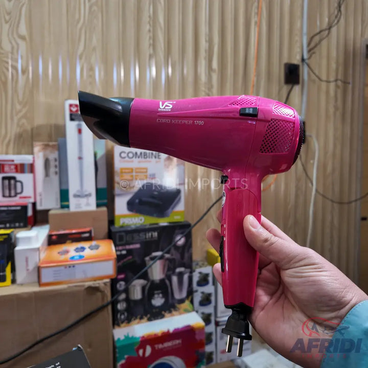 A bright pink electric hair dryer with a black nozzle and a two-prong plug.