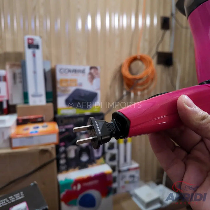 Pink hair dryer with a two-prong electrical plug.