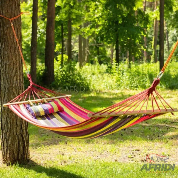 A colorful striped fabric hammock with wooden spreader bars and a small pillow.