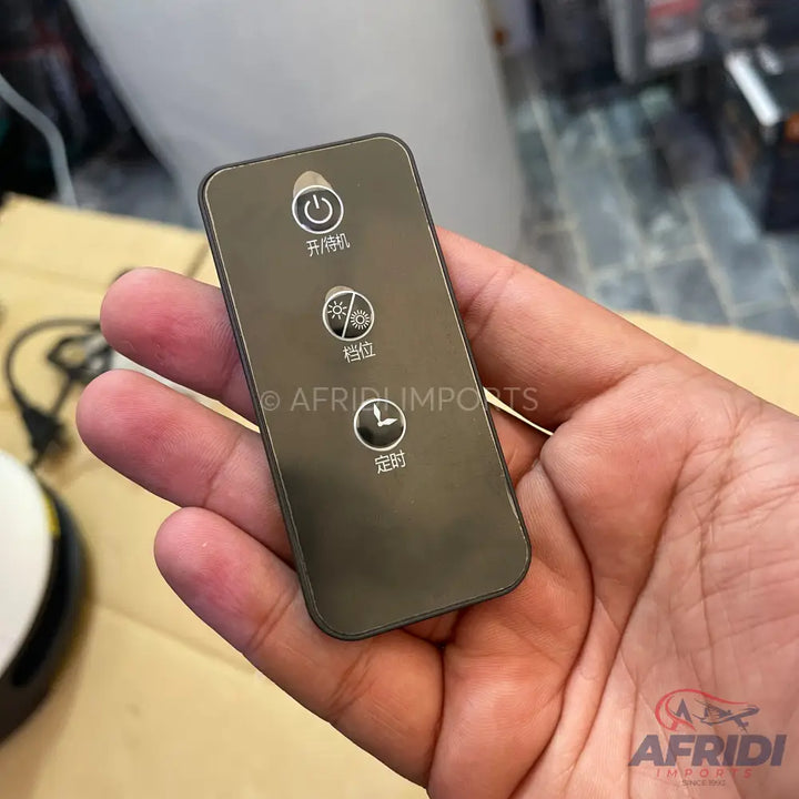 A dark gray remote control with three circular buttons featuring power, fan speed, and timer functions.