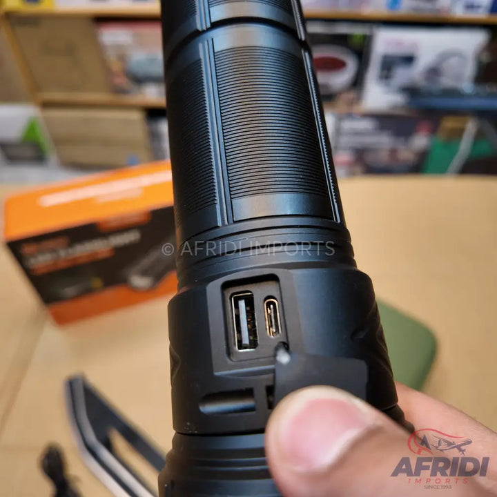 Black tactical flashlight with USB-A and USB-C charging ports.