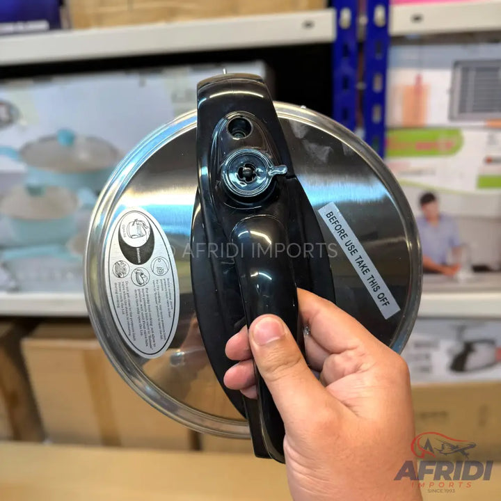 Stainless steel pressure cooker lid with a black handle.