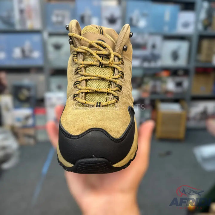 A tan suede hiking boot with black accents and yellow laces.