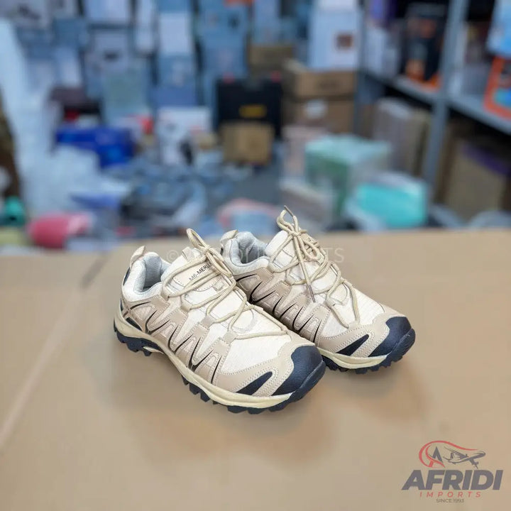 Pair of light brown hiking shoes with dark blue accents.