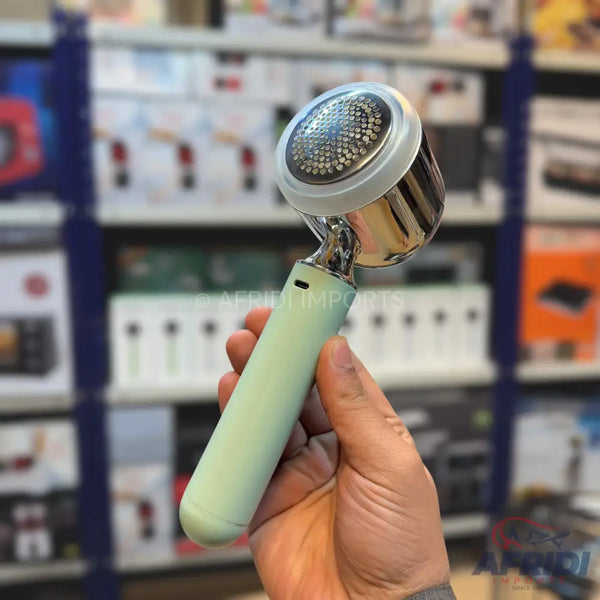 A handheld, light green, electric lint remover with a metallic silver head.