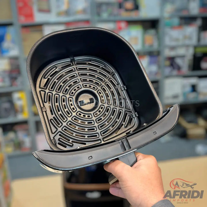 Black air fryer basket with a removable crisping plate.