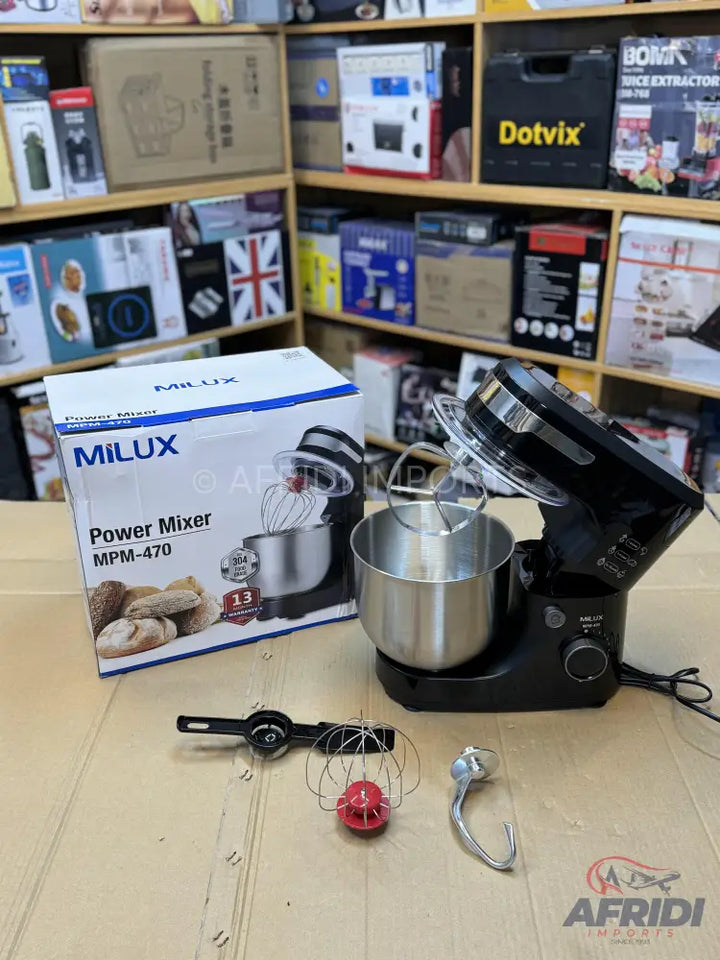 A black stand mixer with a stainless steel bowl and various attachments, displayed with its packaging.