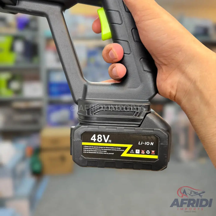 A black, handheld, battery-powered pressure washer with a green trigger.