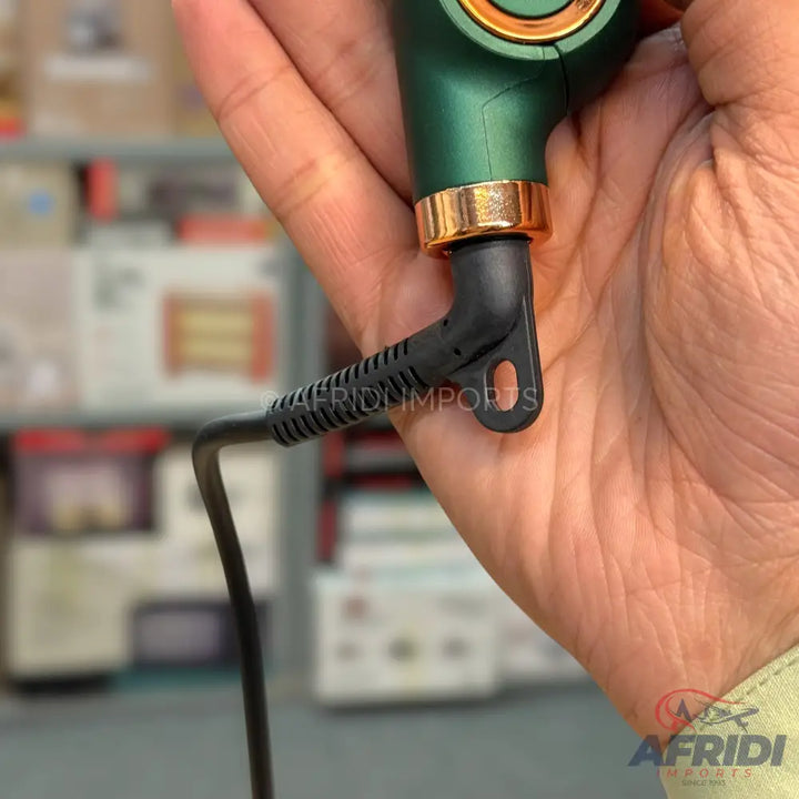 A handheld green and gold electronic device with a black power cord.