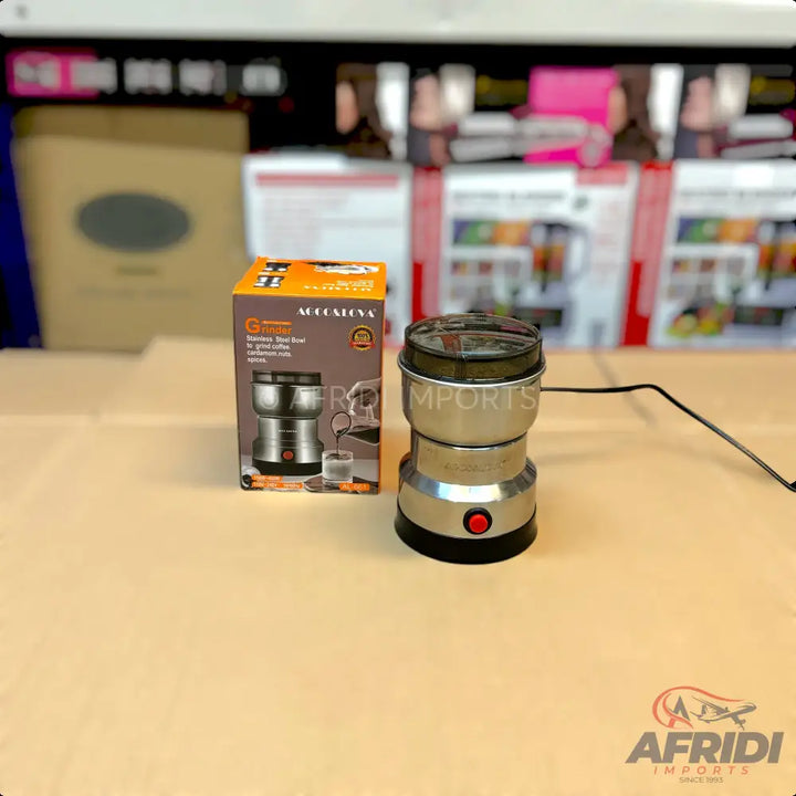 Stainless steel electric coffee grinder with a clear lid and red power button.
