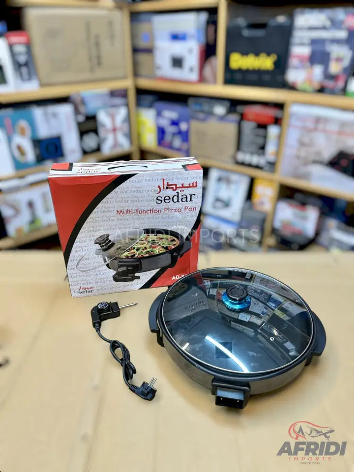 A multi-function electric pizza pan with a clear glass lid and a detachable power cord.