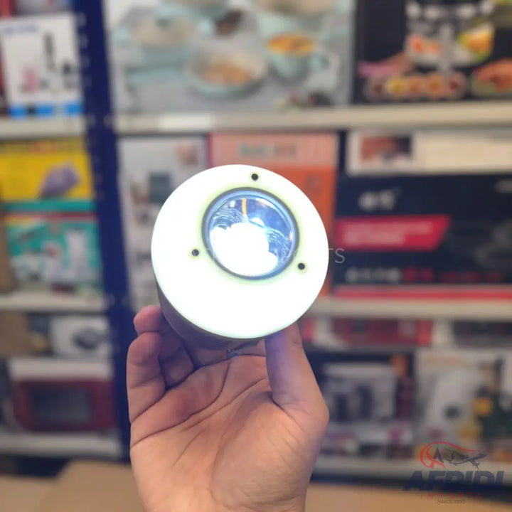 A white, circular, hand-held LED light.