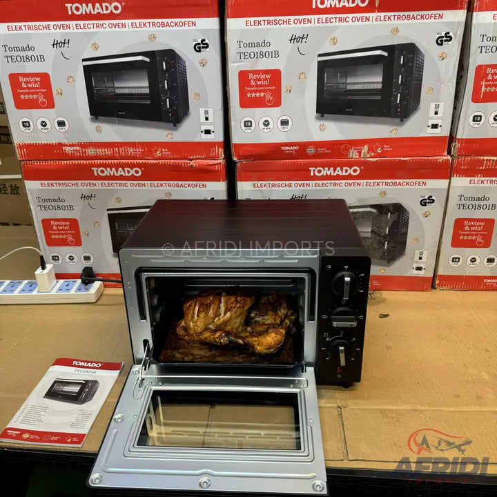 A black and silver electric oven with a whole roasted chicken inside.