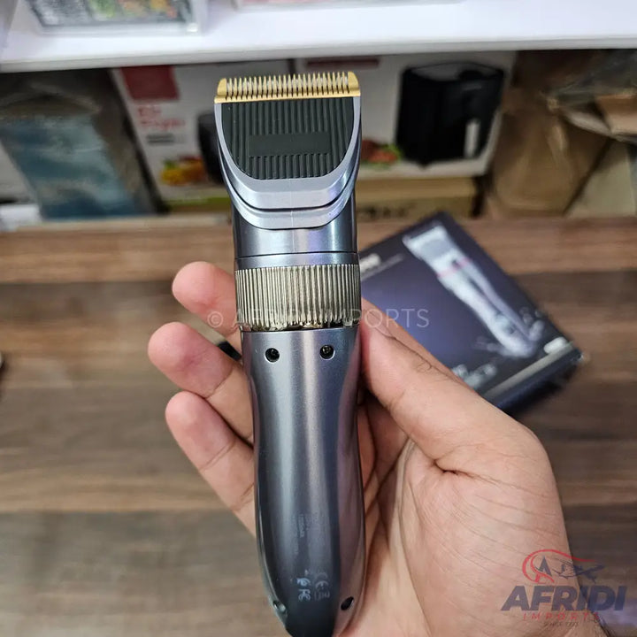 A metallic gray hair clipper with a gold-colored blade.