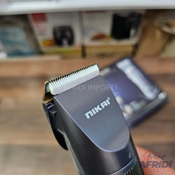 Dark gray electric hair clipper with a white ceramic blade.