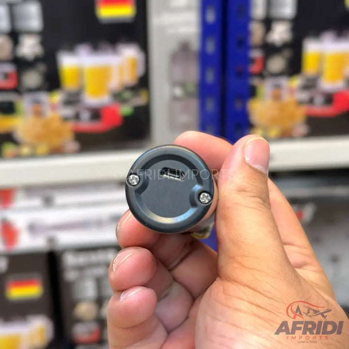 A dark grey, cylindrical, handheld device with a charging port and two screws on one end.