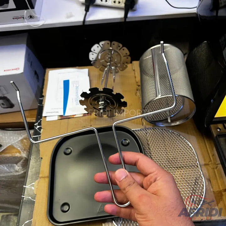 An air fryer accessory kit including a rotisserie spit, a mesh basket, and a drip pan with a handle.