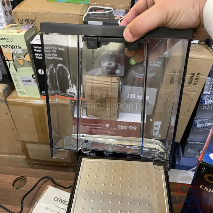 A clear plastic and black espresso machine with a metallic perforated drip tray.