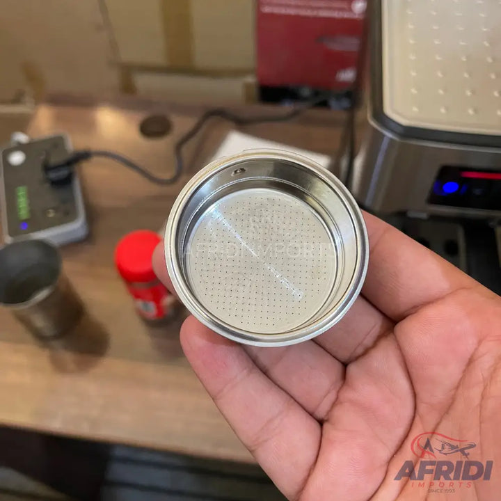 A stainless steel espresso filter basket with a perforated bottom.