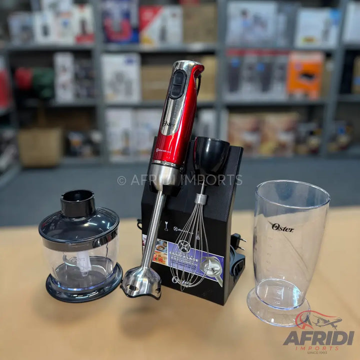 A red and silver immersion blender with multiple attachments including a whisk, a chopper, and a measuring cup.