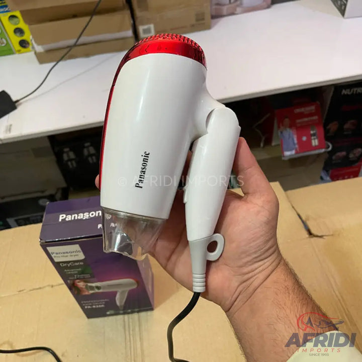 White and red hair dryer with a folding handle and an attached power cord.