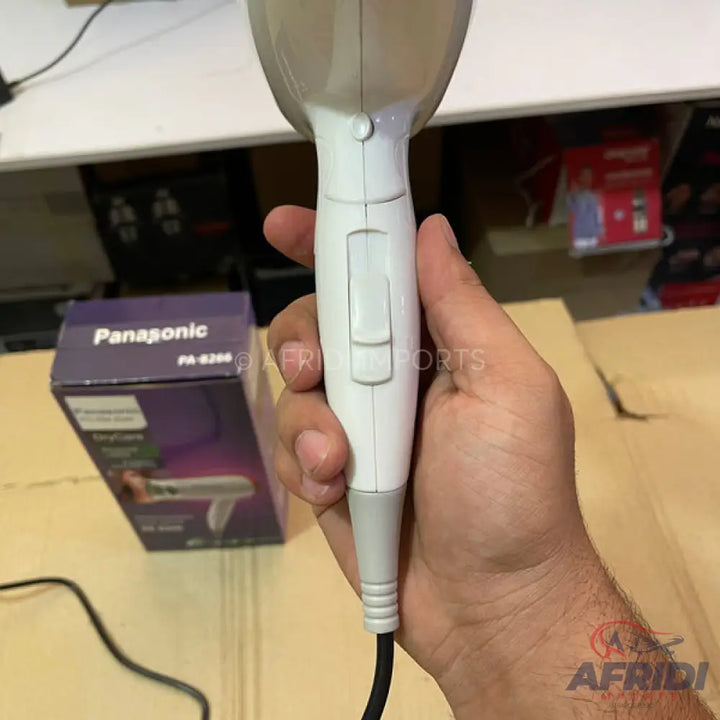 A white hair dryer with a gray power cord.