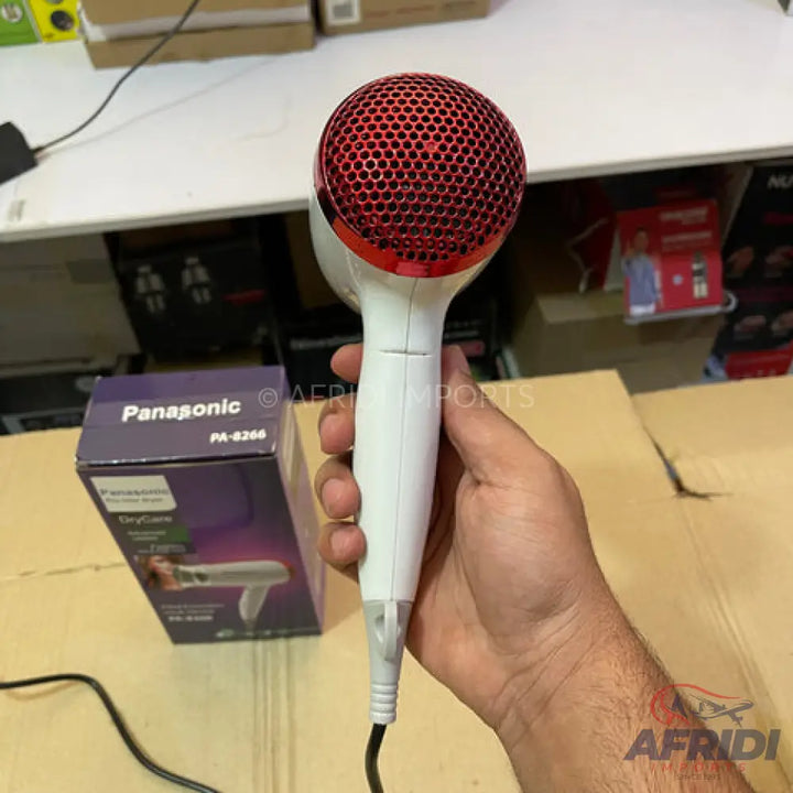 White hair dryer with a red, honeycomb-patterned grille.
