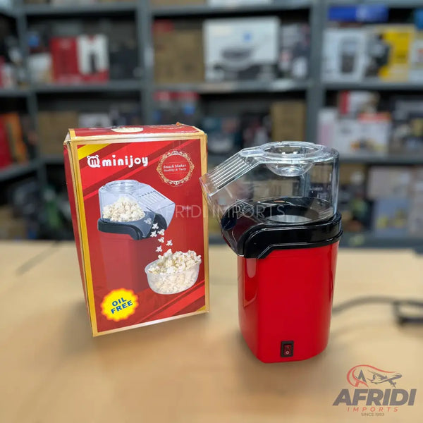 Red electric popcorn maker with a clear lid, designed for oil-free popping.