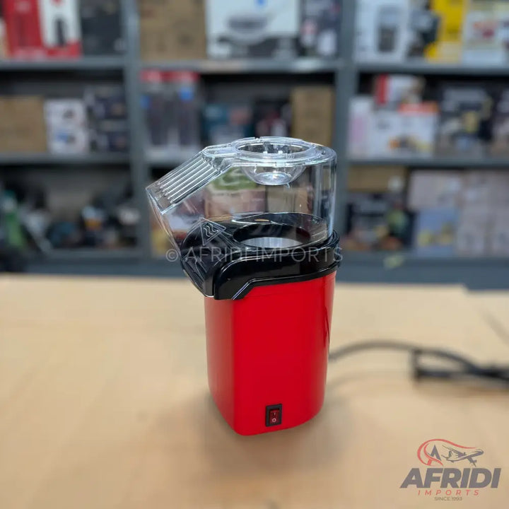 Red electric popcorn maker with a clear plastic top.