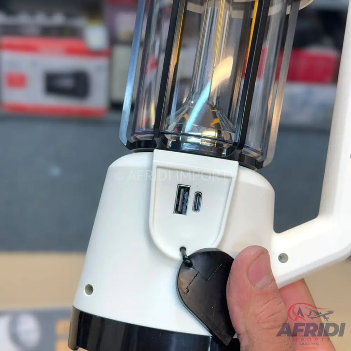 A white and black lantern with clear panels, featuring two USB ports and a black pull tab.