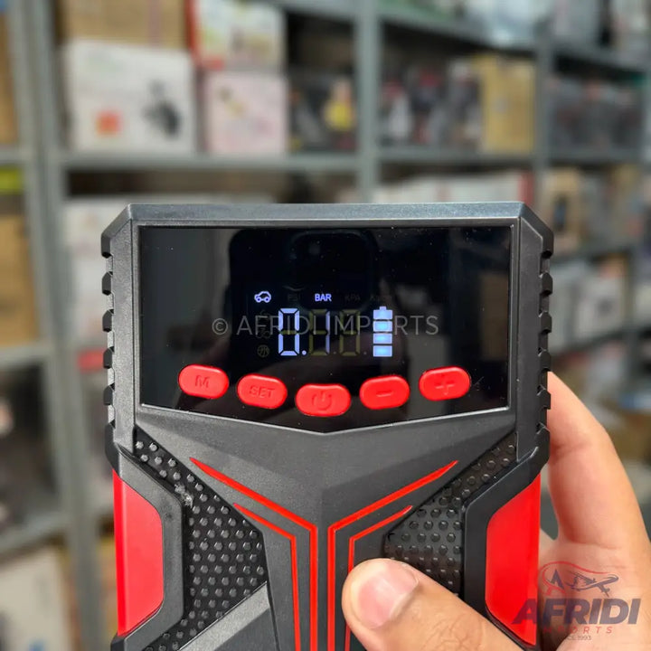 A handheld portable air compressor with a digital display and red control buttons.