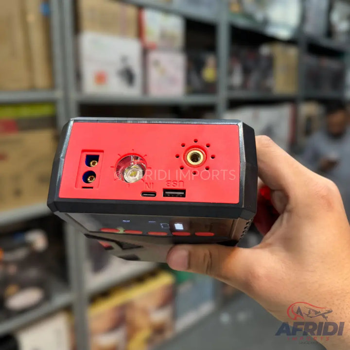 A red and black portable power station with multiple ports including USB, DC, and a car jump starter connection.