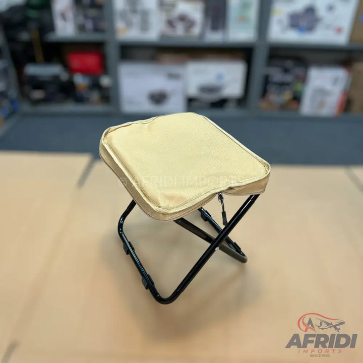 A foldable camping stool with a padded, beige seat.