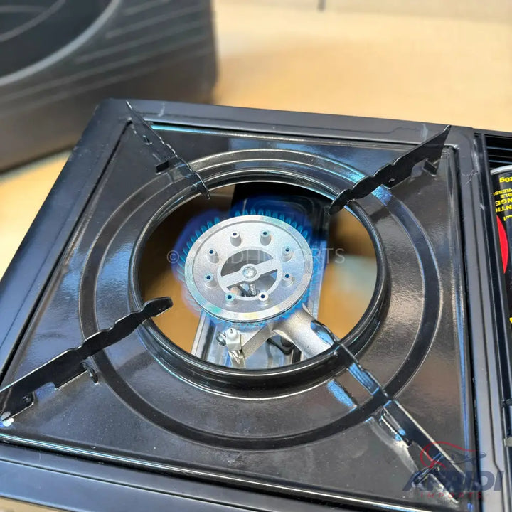 A portable gas stove with a lit burner.