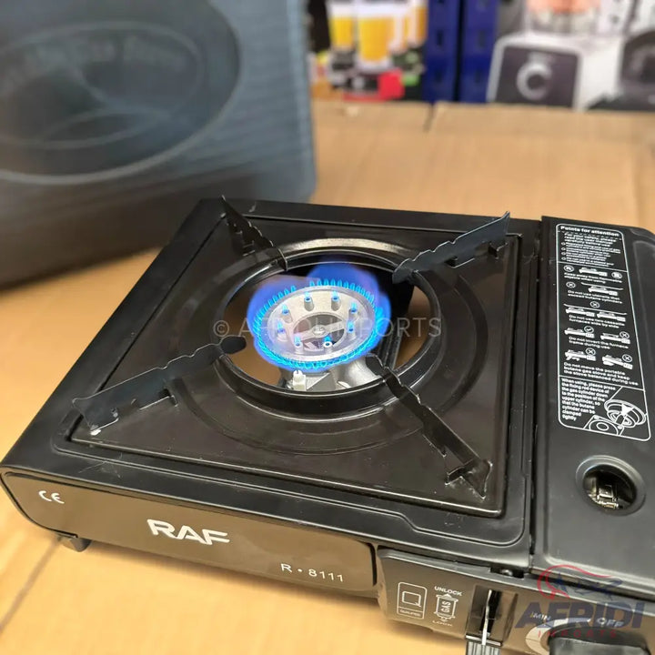 A black portable gas stove with a lit blue flame, featuring a single burner and a control knob.