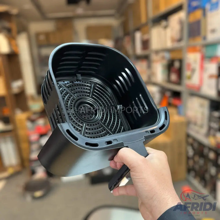 Black air fryer basket with a perforated base and handle.