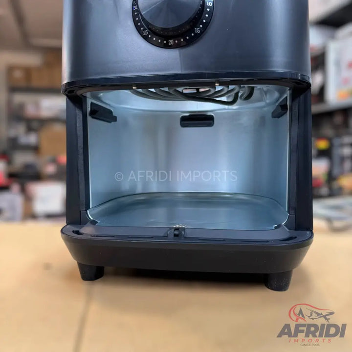 An empty dark grey air fryer with a stainless steel interior and a visible heating element, featuring a timer dial on top.