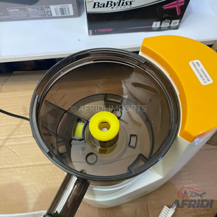 A transparent dark grey juice extractor with a yellow central component and an orange lid.