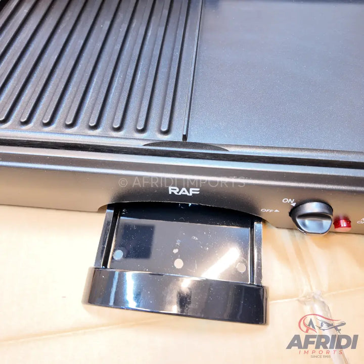 A black electric indoor grill with both ribbed and flat cooking surfaces, featuring a removable drip tray and an on/off dial.