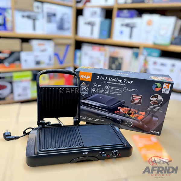 A black 2-in-1 electric grill and baking tray with an open lid and a power cord.