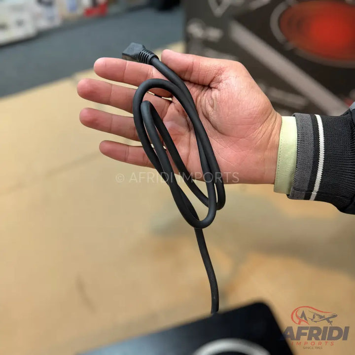 A person holding a coiled black cable with a small, flat connector.