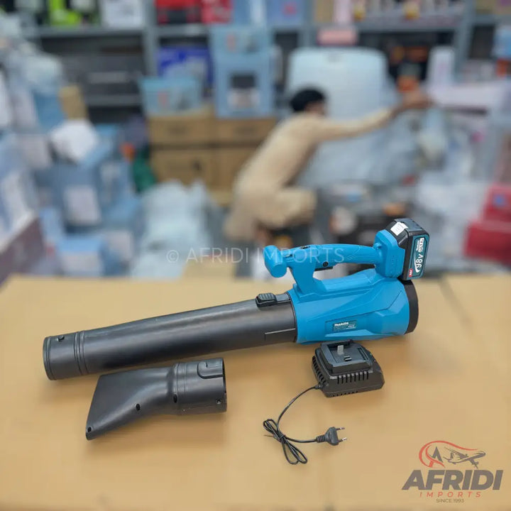 Cordless teal and black leaf blower with a detachable nozzle and charger.