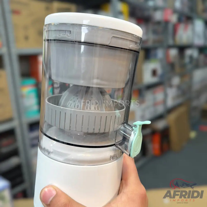Portable electric juicer with a clear container and a light blue spout.