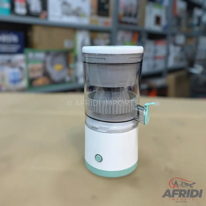 A compact, electric citrus juicer with a clear top and a white and mint green base.