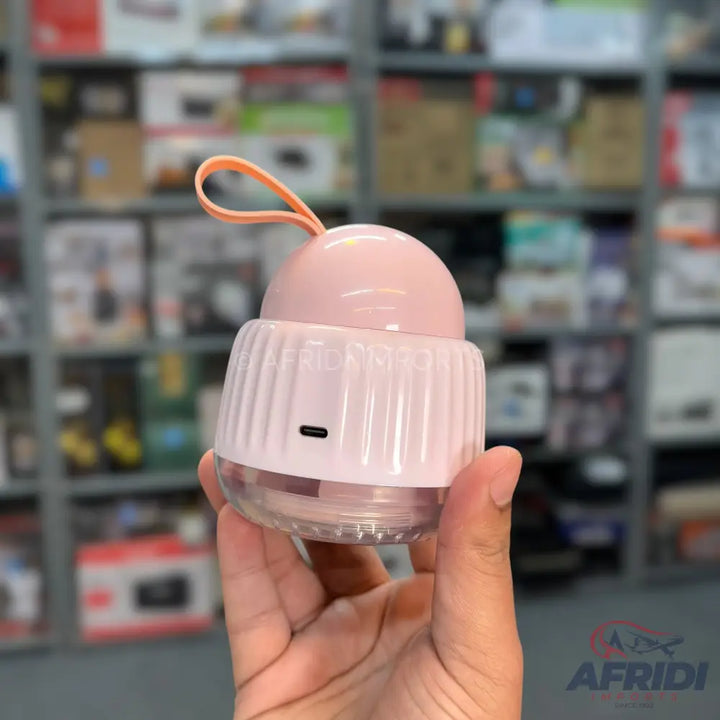 A handheld pink lint remover with a clear base and a USB-C charging port.