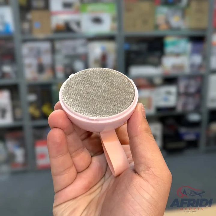 Pink portable lint remover with a textured scrubbing surface.