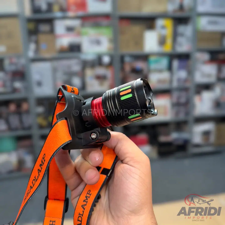 An orange and black headlamp with a red and black flashlight.