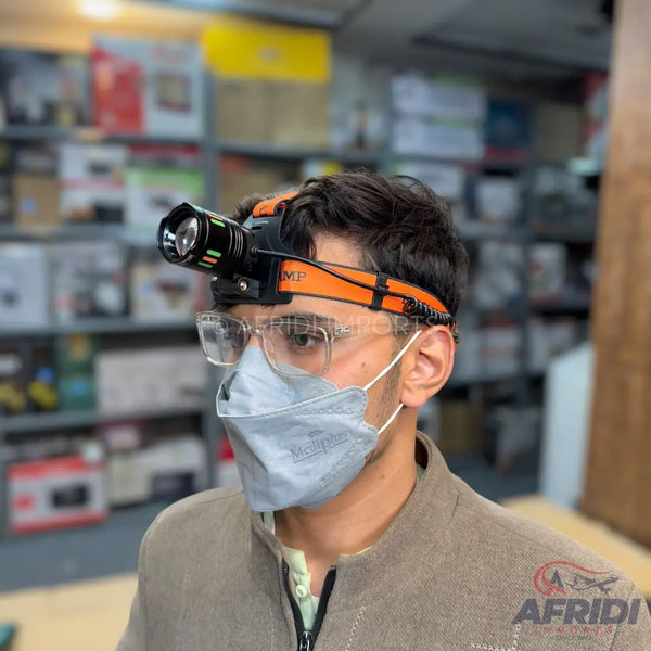 A person wearing a headlamp, face mask, and glasses.