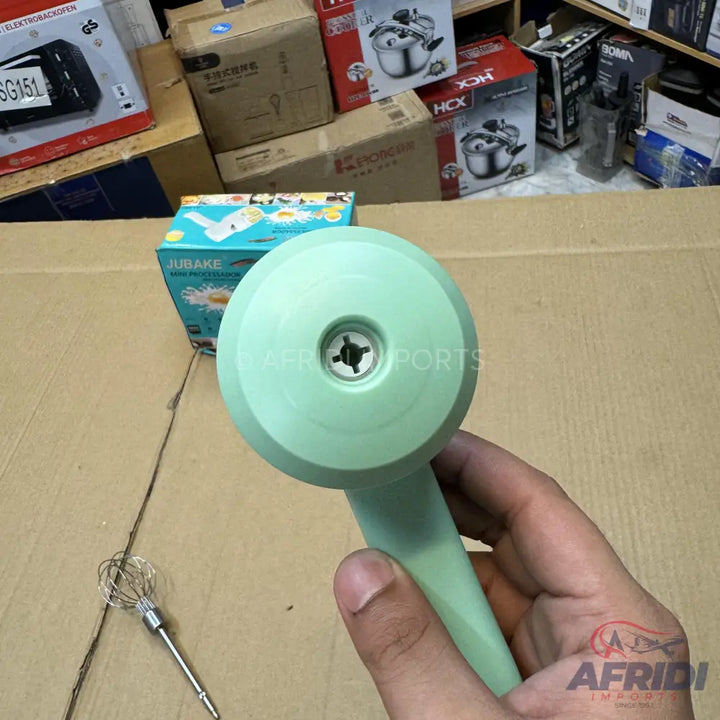 A light green handheld electric whisk or mixer with a removable attachment for whipping.